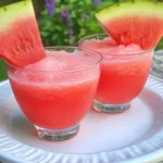 Fresh watermelon slushie recipe in glasses with watermelon wedge garnish on white plate
