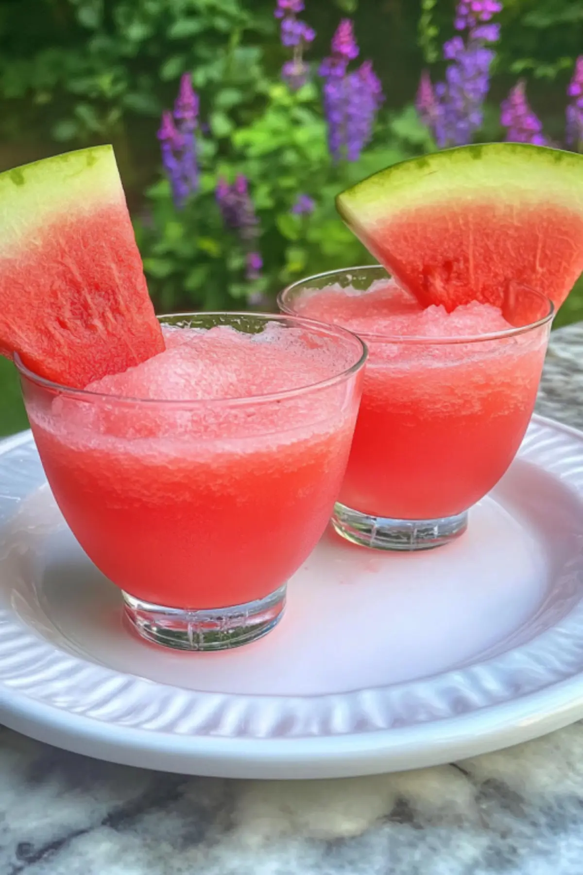 Fresh watermelon slushie recipe in glasses with watermelon wedge garnish on white plate