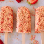 Homemade strawberry shortcake ice cream bars with cookie crumb coating and fresh strawberries on white background