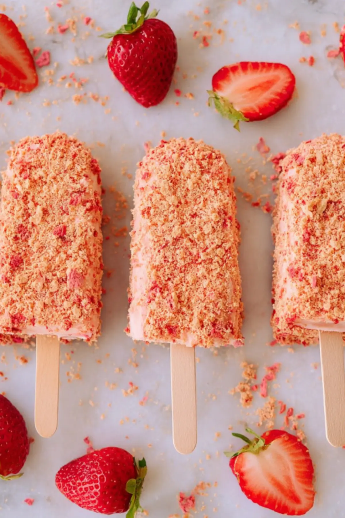 Homemade strawberry shortcake ice cream bars with cookie crumb coating and fresh strawberries on white background