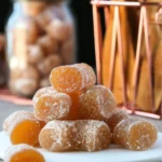 Homemade honey ginger chews candy dusted with cornstarch arranged on white plate with mason jar storage