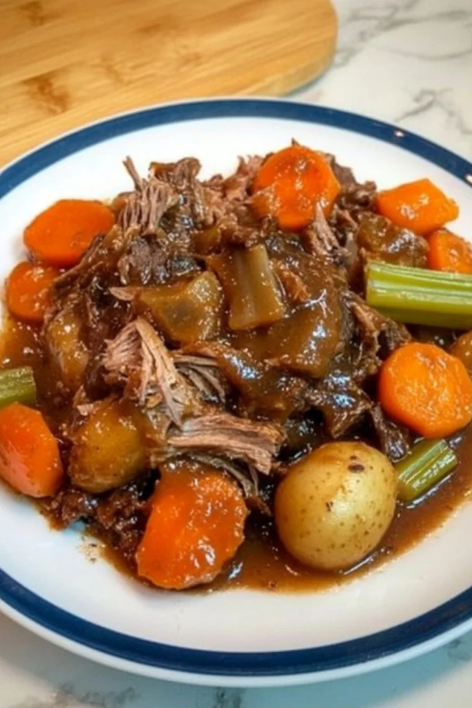Tender slow cooker pork and beef roast with carrots, potatoes, onions and celery in rich brown gravy on white plate