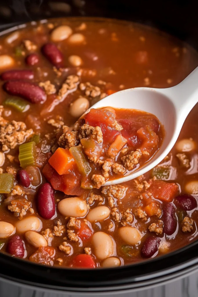 Hearty slow cooker chili soup with ground beef, kidney beans, white beans, diced tomatoes and vegetables being served with a ladle