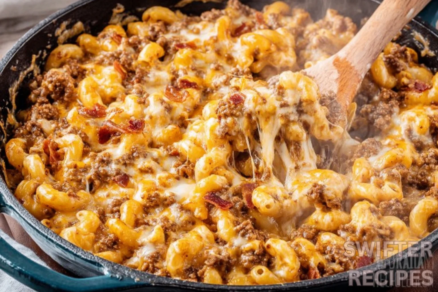Bacon cheeseburger casserole with melted cheese and ground beef in cast iron skillet with wooden spoon