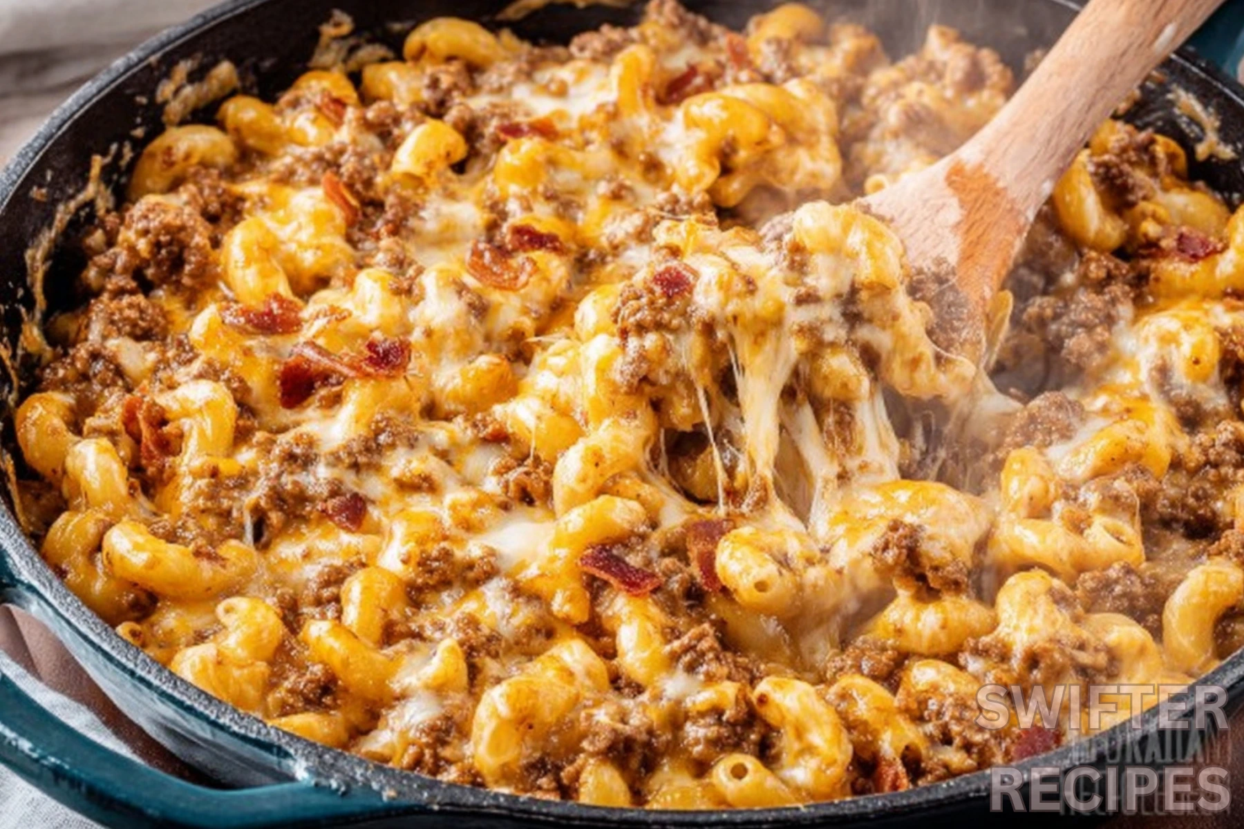 Bacon cheeseburger casserole with melted cheese and ground beef in cast iron skillet with wooden spoon