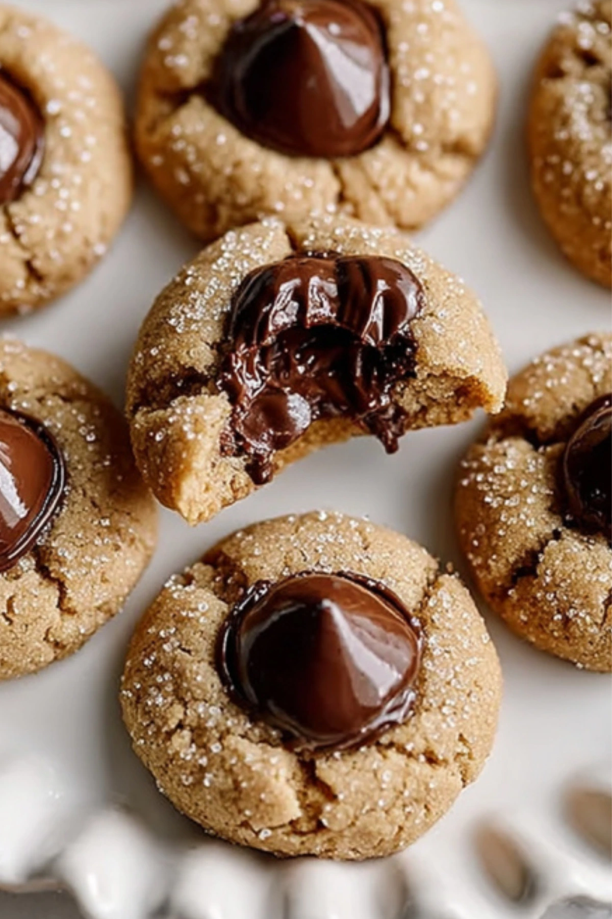 Sugar-coated peanut butter cookies with melted chocolate candy centers showing gooey chocolate filling, one cookie broken in half