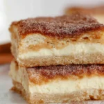 Churro Cheesecake slices with a golden cinnamon-sugar crust and creamy cheesecake filling, stacked on a plate, perfect for dessert lovers.