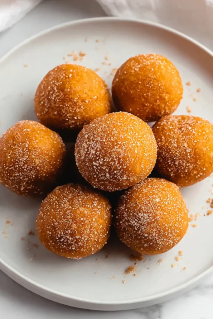 Keto pumpkin fat bombs rolled in cinnamon spice and sweetener on a white plate