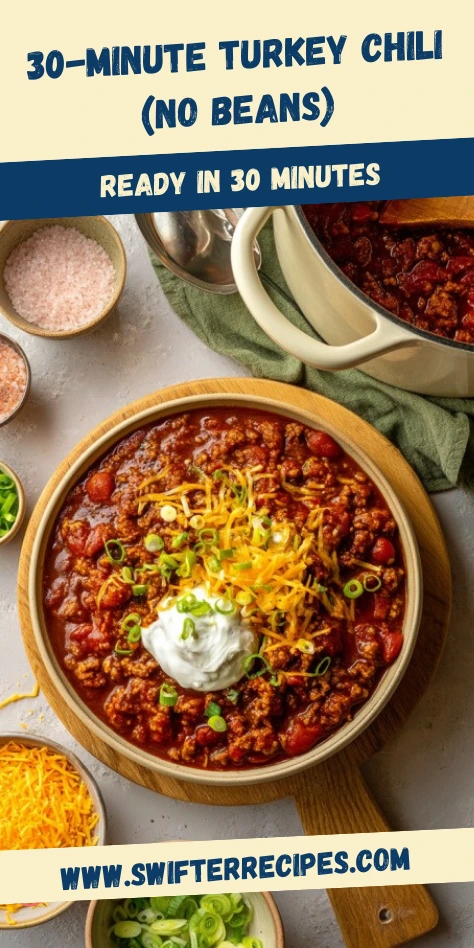 Turkey Chili (No Beans) vertical Pinterest pin showing a hearty bowl topped with shredded cheese sour cream and green onions beside a cream Dutch oven