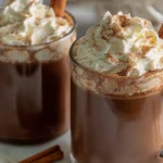 Creamy Pumpkin Spice Hot Chocolate topped with whipped cream, cinnamon, and a cinnamon stick, perfect for fall.