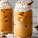 Iced Pumpkin Spice Latte Cold Brew with whipped cream, cinnamon, and ice cubes in a glass jar.