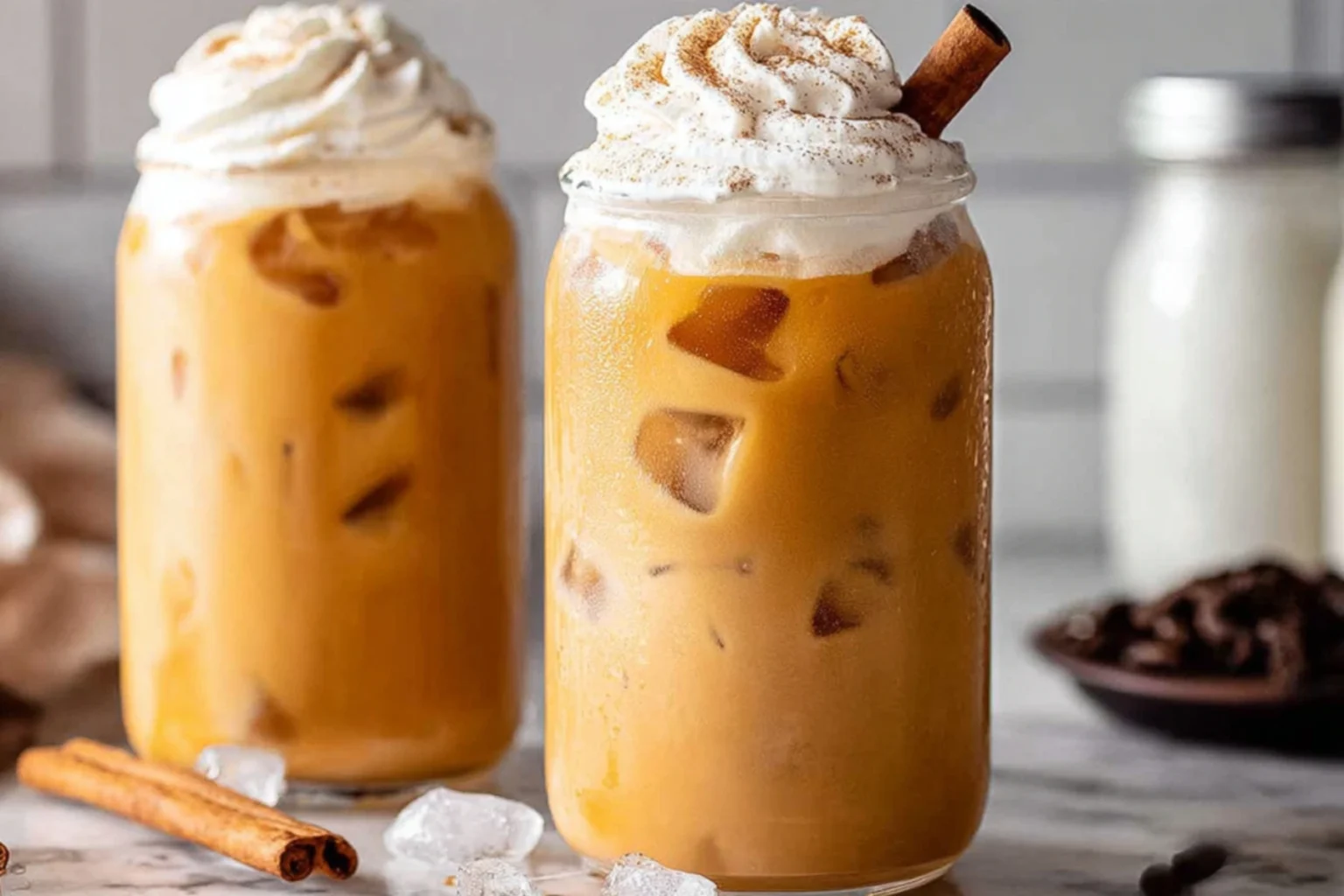 Iced Pumpkin Spice Latte Cold Brew with whipped cream, cinnamon, and ice cubes in a glass jar.