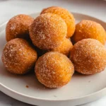 Keto Pumpkin Fat Bombs stacked on a white plate coated with cinnamon spice and sweetener
