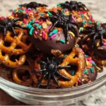 Spooky Spider Pretzel Mix with chocolate-covered pretzels, rainbow sprinkles, and gummy spiders served in a glass bowl on marble countertop