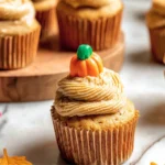 Delicious pumpkin cupcakes topped with spiced cream cheese frosting and a mini pumpkin decoration. A perfect fall dessert!