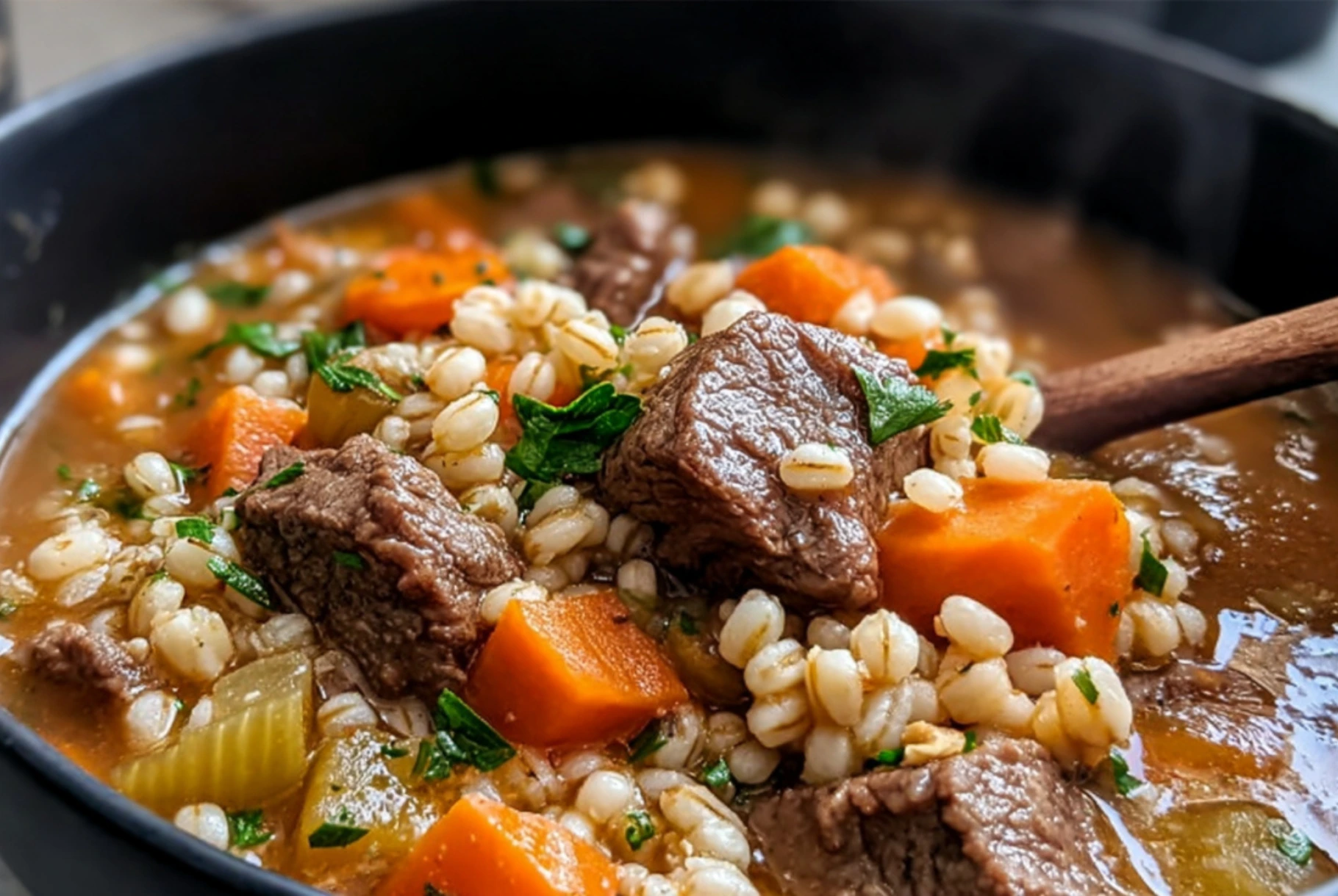 Beef and barley stew with tender beef cubes, carrots, celery, and pearl barley in a hearty broth served in a rustic bowl