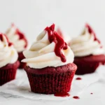 Halloween Red Velvet Cupcake with cream cheese frosting and raspberry sauce drizzle, spooky dessert idea for Halloween parties