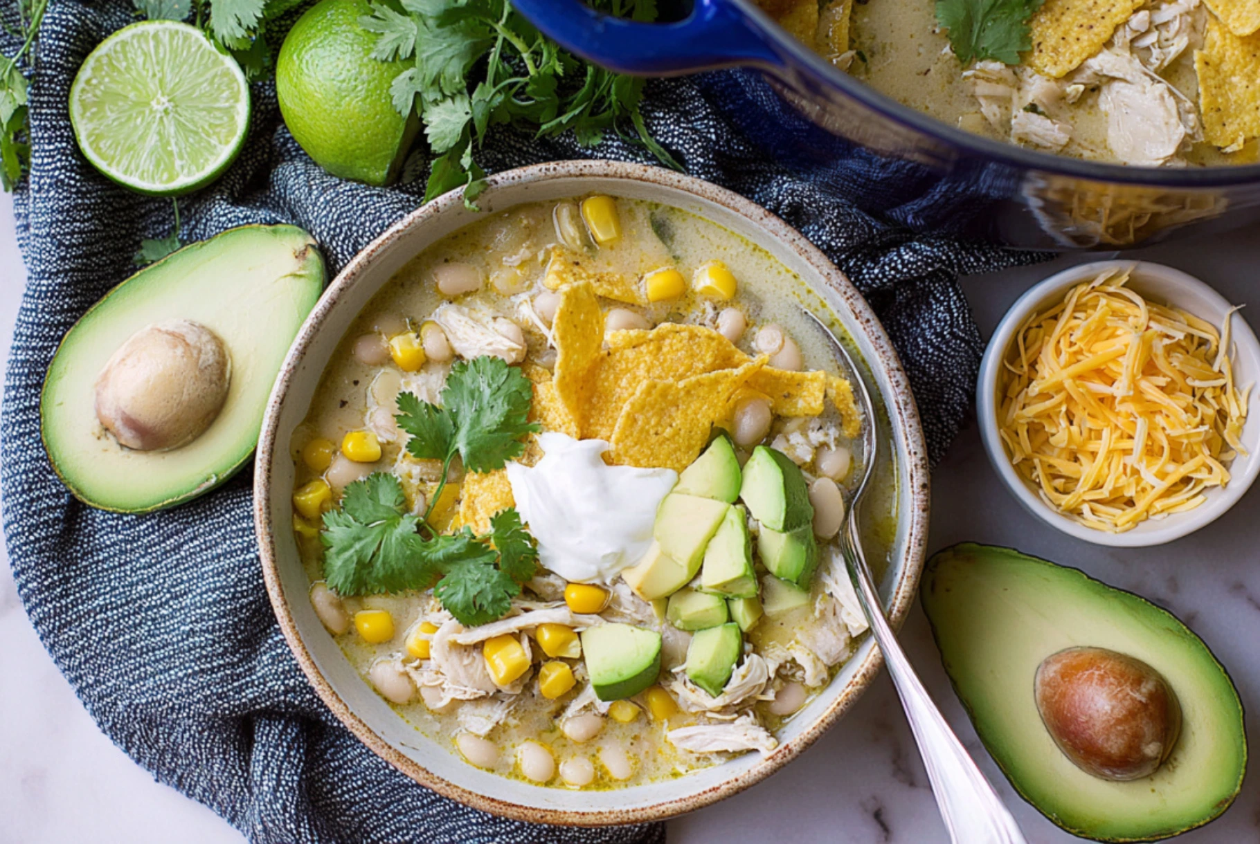 White Chicken Chili with Green Chiles topped with avocado, tortilla chips, cilantro, and sour cream