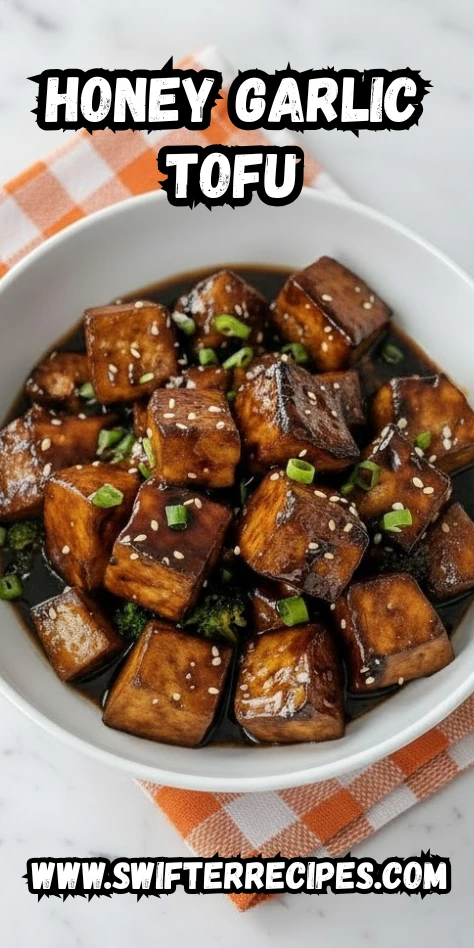 Crispy honey garlic tofu cubes coated in sticky soy-honey glaze topped with sesame seeds and green onions served in a white bowl.