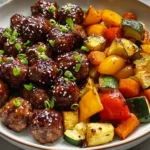 BBQ meatballs with roasted vegetables including zucchini, carrots, and bell peppers in a bowl.