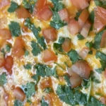 Cheesy refried bean dip topped with melted cheddar, Monterey Jack cheese, fresh tomatoes, and parsley baked until golden and bubbly.