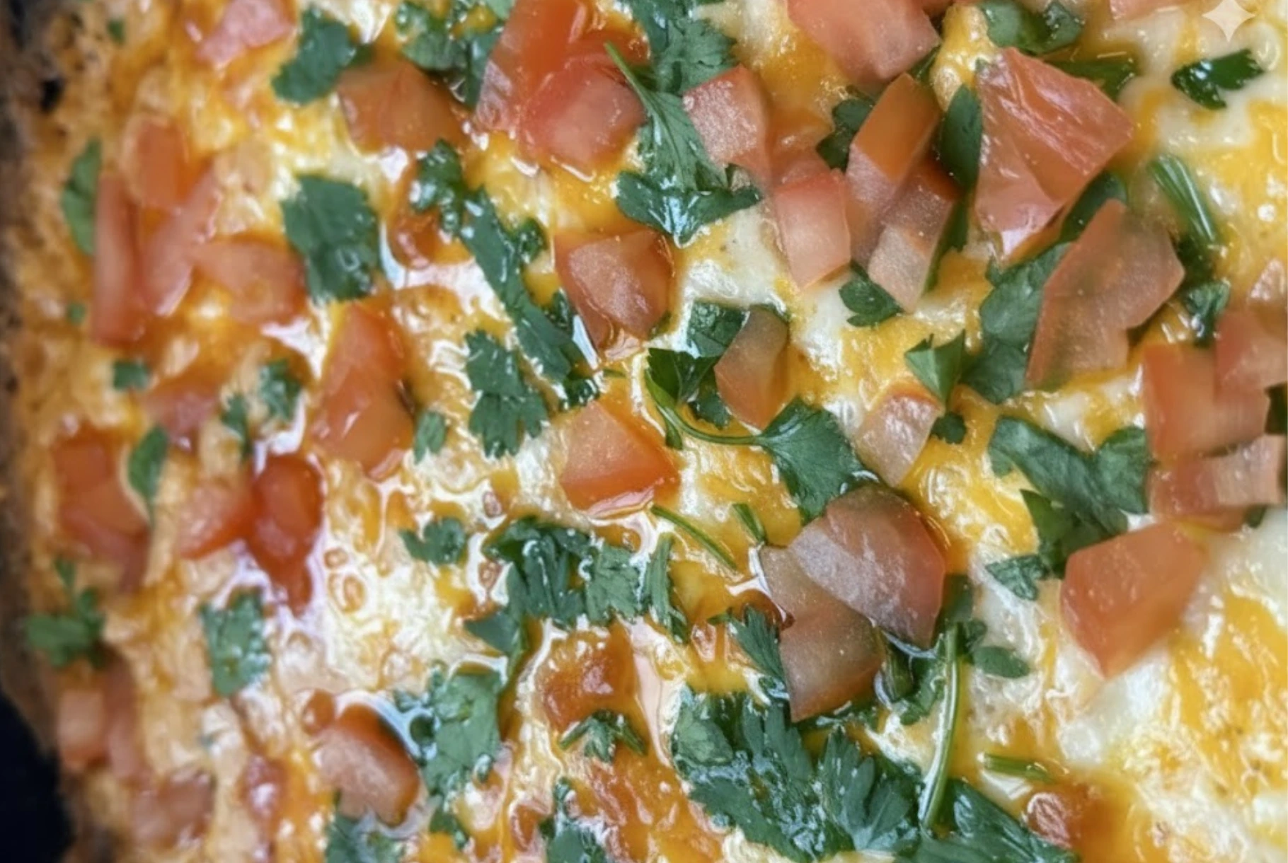 Cheesy refried bean dip topped with melted cheddar, Monterey Jack cheese, fresh tomatoes, and parsley baked until golden and bubbly.