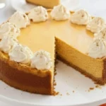 Pumpkin Cheesecake Swirl with creamy whipped topping and graham cracker crust on a white cake stand