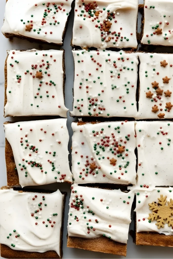 Top view of frosted gingerbread cookie bars cut into squares, topped with cream cheese frosting and festive red, green, and white sprinkles.