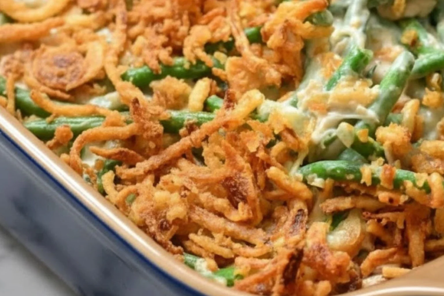 Green bean casserole topped with crispy fried onions in a baking dish