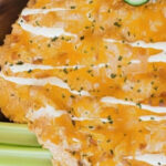 Healthy Buffalo Chicken Dip with Greek Yogurt topped with melted cheddar and creamy ranch drizzle