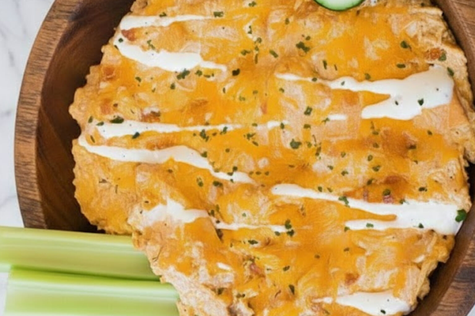 Healthy Buffalo Chicken Dip with Greek Yogurt topped with melted cheddar and creamy ranch drizzle