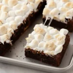 Easy S’mores Brownies topped with toasted mini marshmallows on a baking pan, showing rich chocolate layers and gooey texture.