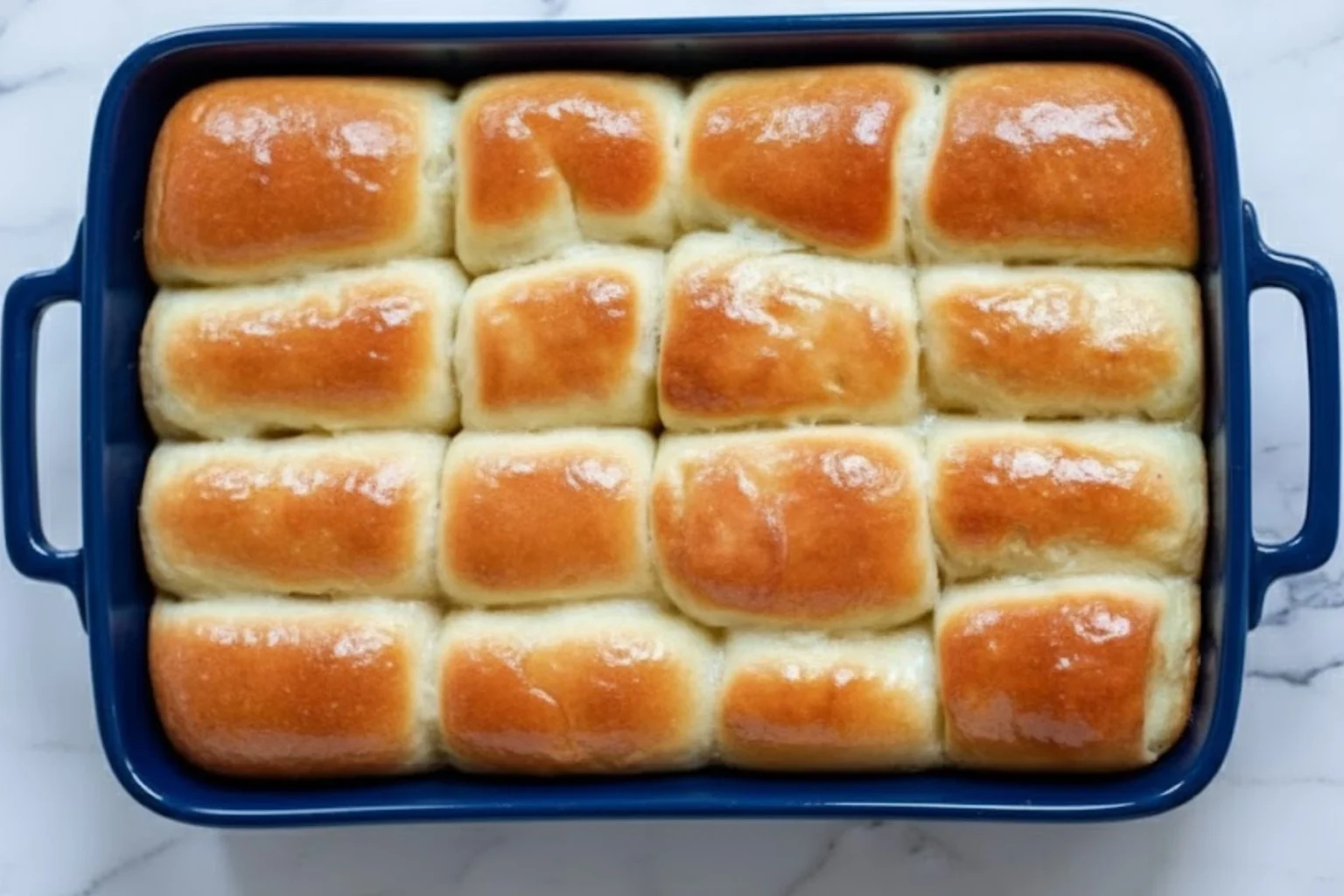 Soft golden Parker House Rolls baked in a blue casserole dish.