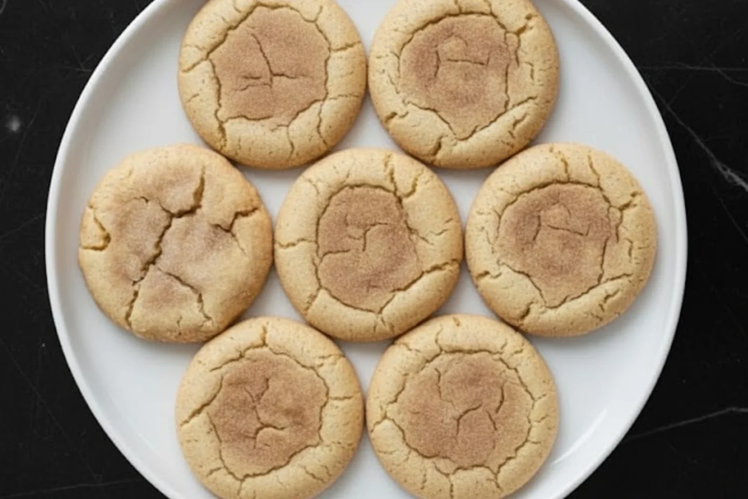Chewy cinnamon sugar cookies on a white plate showing soft centers and cracked edges