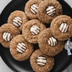 Christmas Kitchen Sink Cookies topped with striped chocolate kisses on a black plate