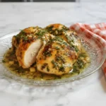 Juicy roasted chicken with garlic herb butter served on a glass plate, garnished with fresh herbs and drizzled with buttery garlic sauce.