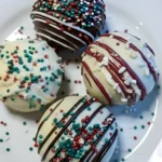 Christmas Oreo Balls coated in white and dark chocolate topped with red and green holiday sprinkles on a white plate