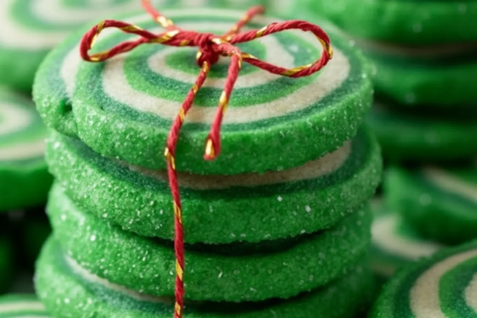 Green Christmas Pinwheel Cookies stacked and tied with red string for a festive holiday treat.