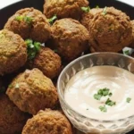 Crispy homemade falafel balls served with creamy tahini sauce in a bowl, garnished with fresh parsley.