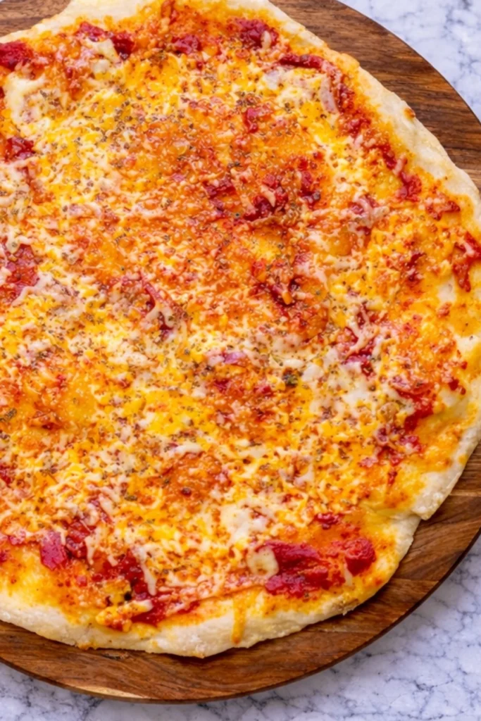 Greek yogurt pizza dough baked into a thin crust cheese pizza with tomato sauce and melted cheese on a wooden board