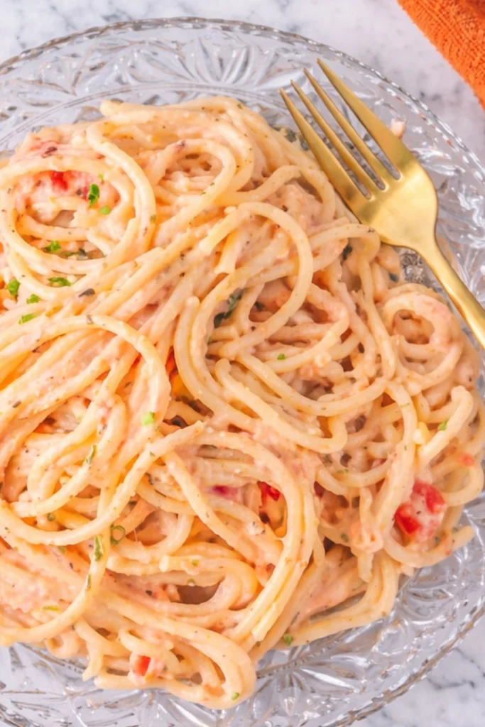 Spaghetti with creamy Italian pink sauce served on a glass plate with a gold fork
