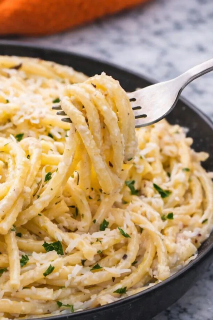 Fork twirling creamy Bucatini Cacio e Pepe with Parmesan and parsley
