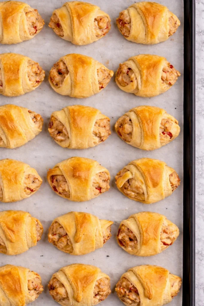 Baked sausage cream cheese crescent rolls arranged on a baking sheet with golden flaky tops