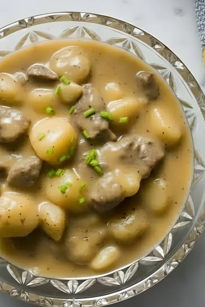 Creamy steak and potato soup with tender beef chunks, soft golden potatoes, and rich savory gravy topped with fresh chives