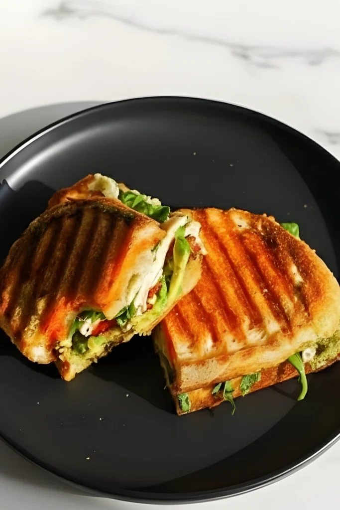 Close-up of Loaded Chicken Pesto Panini with Fresh Greens and Grilled Bread