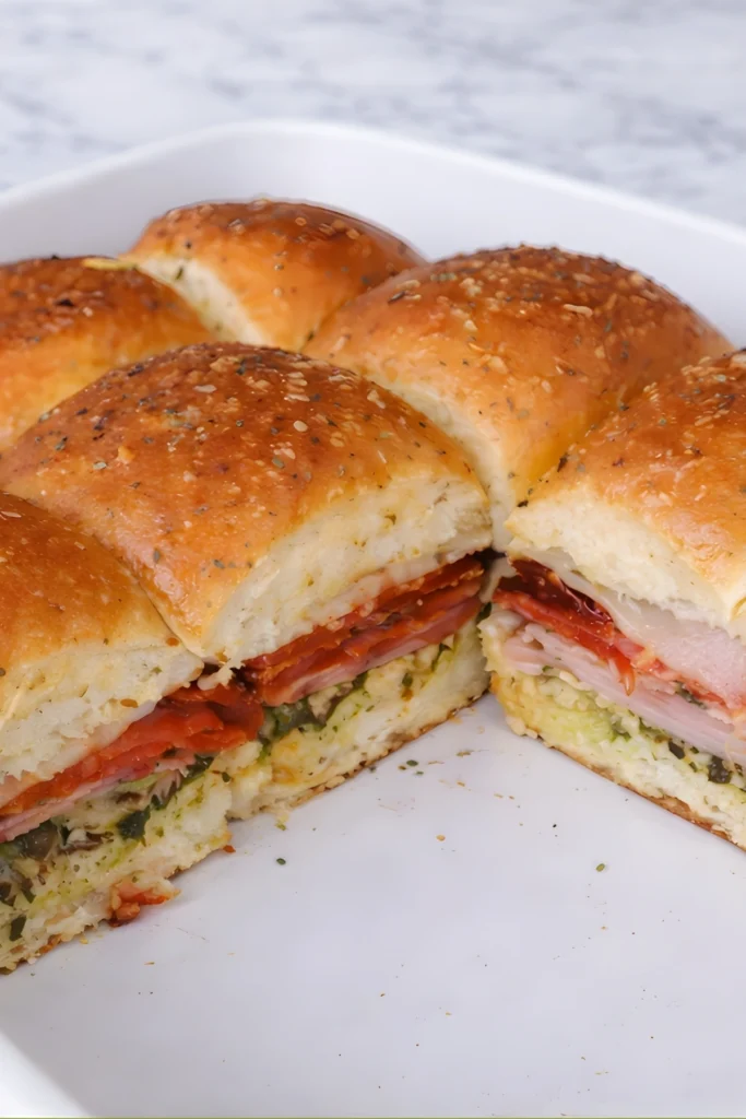 Italian pesto sandwiches sliced open with ham salami pepperoni provolone cheese and pesto on soft golden baked rolls
