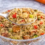 Dirty rice with sausage served in a glass bowl with fluffy long grain rice, browned sausage slices, ground beef, bell peppers, and celery