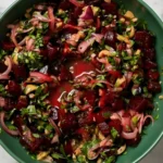 Fresh pickled beet salad with onions, herbs, and pistachios in a green bowl.