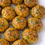 Baked chicken meatballs glazed with garlic butter and herbs served on a white platter