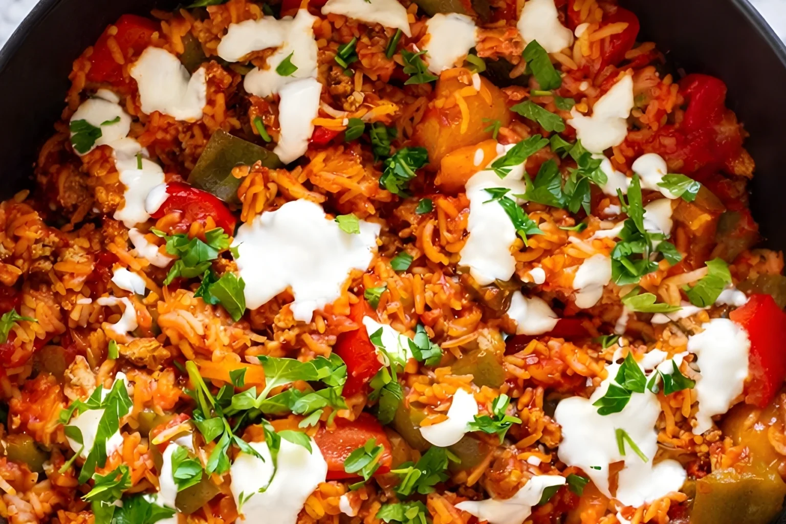 Deconstructed Stuffed Peppers Skillet with ground turkey rice and bell peppers topped with sour cream and fresh parsley in a skillet